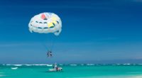 two person riding parachute near beach