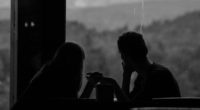 grayscale photography of couple sits by the window